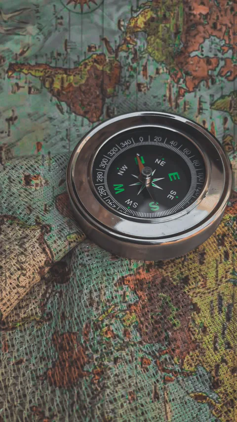 Круглый компас лежит на старинной карте мира